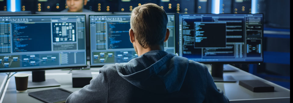 IT and digital forensics specialist working on a computer with screens showing software program with coding language Interface. 